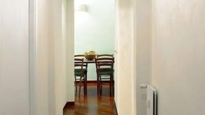 Un couloir étroit mène à une salle à manger où se trouvent une table et des chaises.