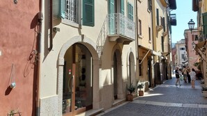 Une rue pavée bordée d’immeubles dotés de portes en arc de cercle et de balcons ornés de rampes en métal.