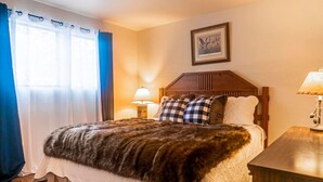 A neatly made bed with a fur throw, a wooden headboard, a bedside lamp, and a framed picture on the wall. - Walk to Bear Mountain-Rustic 3bd sleeps 9 Hot Tub and Fire Pit~0.2 Miles to Bear Mountain (Big Bear Lake)