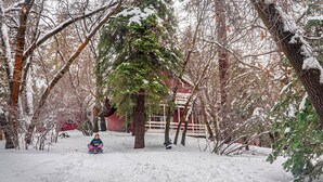 A snow-covered landscape with a red barn and a person sledding. - Walk to Bear Mountain-Rustic 3bd sleeps 9 Hot Tub and Fire Pit~0.2 Miles to Bear Mountain (Big Bear Lake)