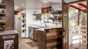 A kitchen with wooden cabinetry, a built-in island, and a view of the outdoors through an open door. - Walk to Bear Mountain-Rustic 3bd sleeps 9 Hot Tub and Fire Pit~0.2 Miles to Bear Mountain (Big Bear Lake)