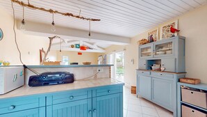 Een keuken met blauwe kastjes, een radio en hangende lampen.
