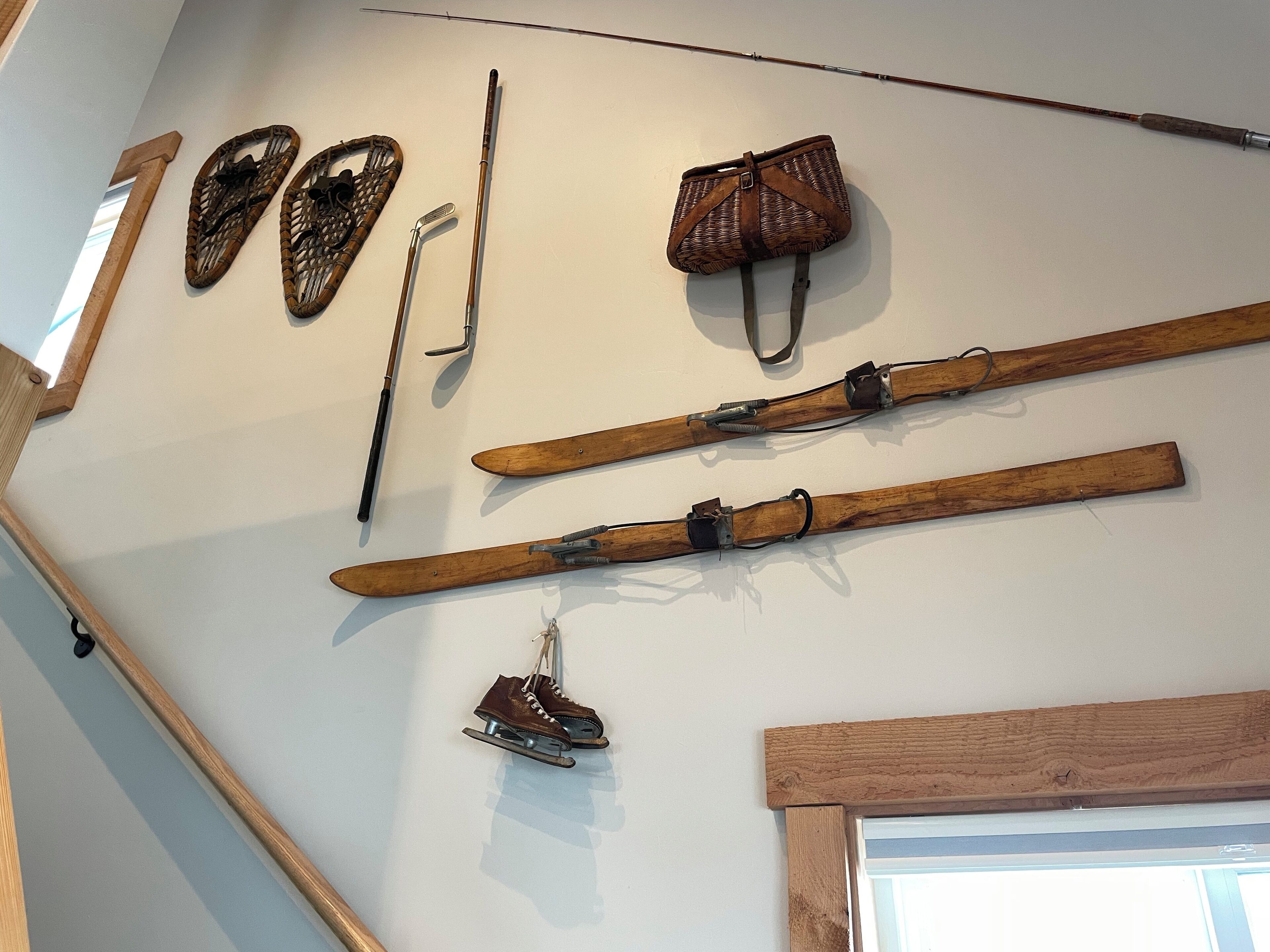 Skis, ski poles, and a pair of ice skates hanging on a wall.