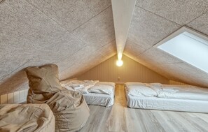 Une chambre mansardée chaleureuse avec un plafond en pente, une lucarne et deux lits.