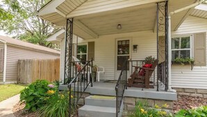 A two-story house with a porch, a wooden fence, and a staircase leading to the front door.