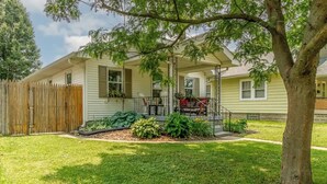A single-story house with a front porch, a wooden fence, and a well-maintained lawn.