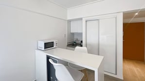 Una kitchenette compacta con microondas, un lavamanos y una pequeña encimera.