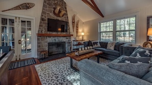 A cozy living room with a stone fireplace, a large window, and a comfortable seating area.