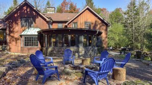 A wooden cabin with a covered porch and blue Adirondack chairs.