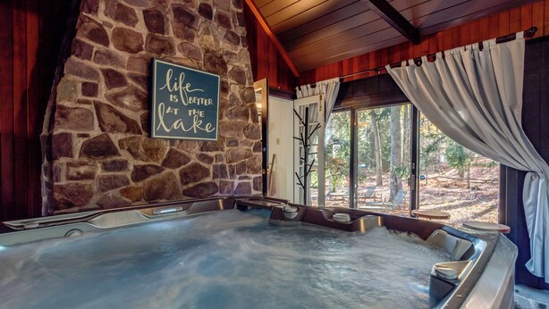 A hot tub with a stone wall and a sign that says "life is better at the lake."