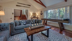 A cozy living room with a sectional sofa, a wooden coffee table, and a pool table.