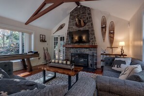 A cozy living room with a stone fireplace, a large TV, and a piano. - Fall In The Poconos, Hot Tub, Game Room, Outside Fire Pit, Sleeps 14 (Lake Harmony)