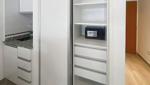 Cozinha com armários brancos, bancada de granito e cofre embutido.