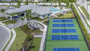 Vue aérienne d’un complexe de courts de tennis comprenant plusieurs terrains, un espace de sièges couvert et une piscine.
