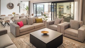 Un salon moderne comprenant un grand ensemble de canapés, une table basse et un coin repas avec une table et des chaises.