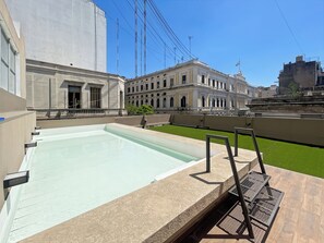 Relax by the pool on this rooftop terrace, featuring a rectangular pool, metal ladder, and comfortable seating area.