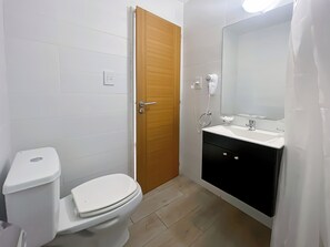 Features a white toilet, sink, and shower area, with a mirror above the sink.