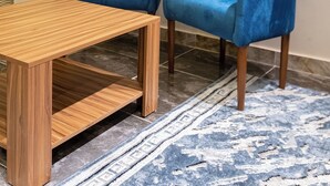 A room with two blue velvet armchairs, a wooden coffee table, and a patterned rug. - Alba pyramids view inn (Giza)