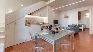 Une cuisine moderne avec un coin repas, des meubles blancs et un escalier.