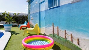 A colorful outdoor play area with a pool, inflatable slides, and beach-themed murals on the walls. - Apart. with 4 suites, 10 people with saltwater pool and barbecue in the Algarve (Quarteira)