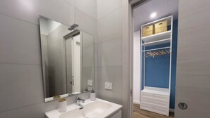 Un baño moderno con lavamanos, espejo y armario de almacenamiento blancos.
