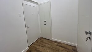 Un pasillo con dos puertas blancas, piso de madera y una lámpara en el techo.