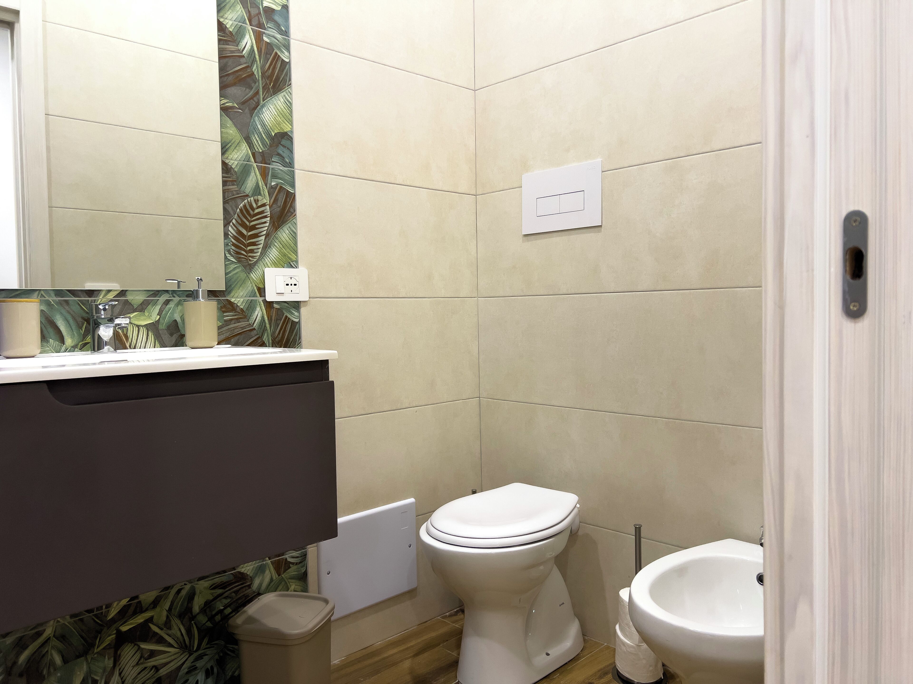 Een badkamer met toilet, bidet, wastafel en spiegel.