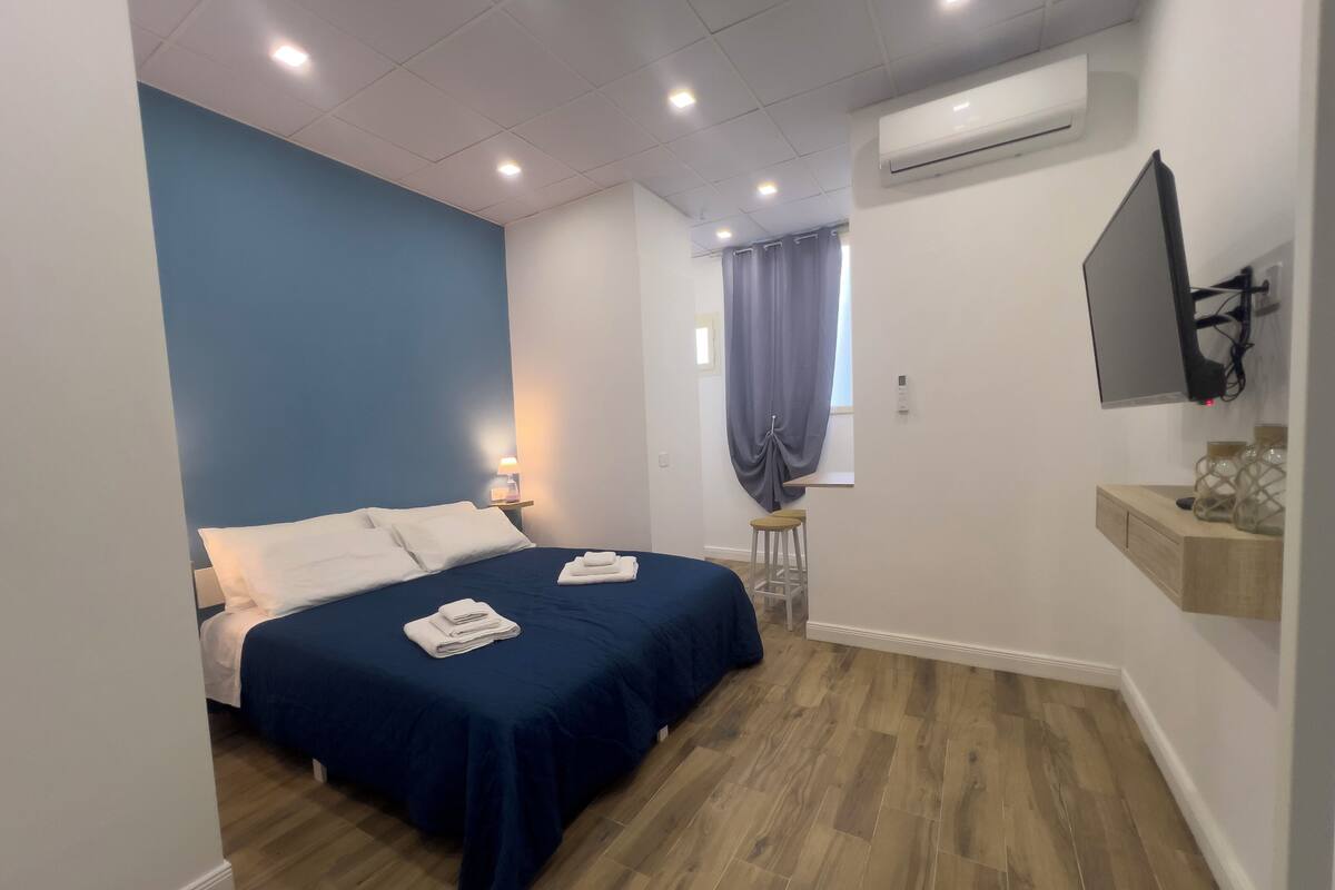 Une chambre d’hôtel équipée d’un lit, d’une table de chevet, d’une chaise, d’un téléviseur et d’un appareil de climatisation.