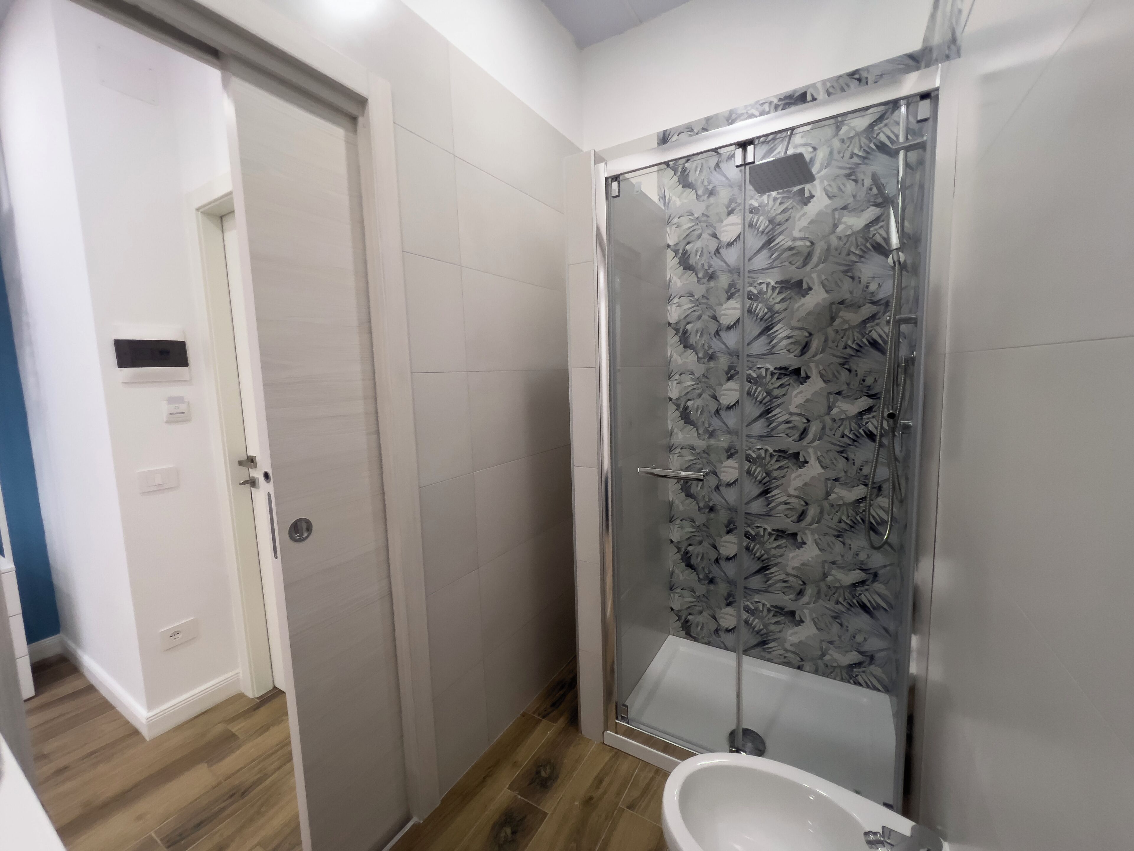 A bathroom with a glass shower enclosure, a toilet, and a sink.