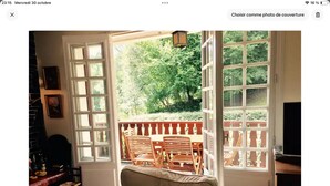 A room with a beige sofa, a wooden dining table with chairs, and a view of greenery through large windows. - Large, comfortable house in Bagneres  (Bagnères-de-Bigorre)