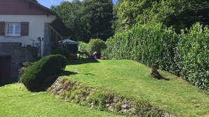 A residential property with a well-maintained lawn, a stone wall, and a house with a chimney. - Large, comfortable house in Bagneres  (Bagnères-de-Bigorre)