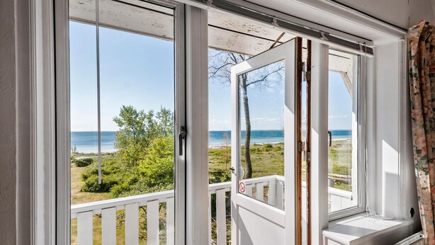 A room with a large window overlooking a beach and ocean.