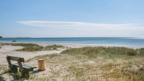 A beach with a bench and a wooden post.
