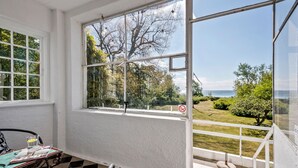 A room with a large window overlooking a garden and the sea.