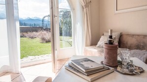 A room with a table, books, a wine bottle, and a view of a garden and mountains. - Nice apartment in Murzasichle with sauna (Murzasichle)