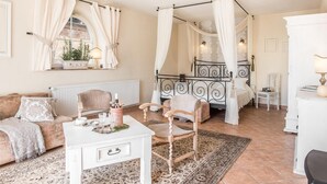 A cozy bedroom with a four-poster bed, a sitting area with a white table, and a window with curtains. - Nice apartment in Murzasichle with sauna (Murzasichle)