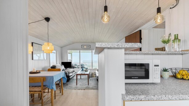 Une cuisine moderne dotée d’un four à micro-ondes encastré, un coin repas avec une table et des chaises, et une vue sur l’extérieur.
