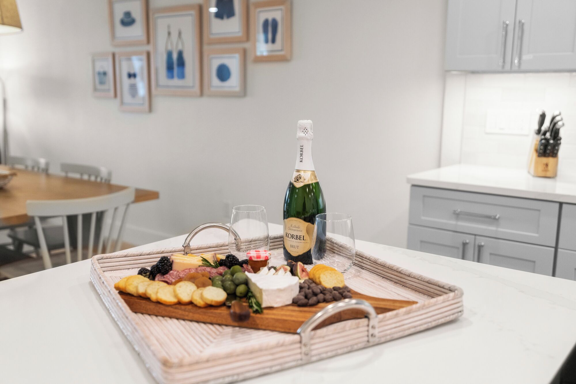 Une table avec une bouteille de champagne Korbel Brut, des verres et une planche de charcuterie comprenant divers fromages, fruits et biscuits salés.