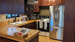 Una cocina con gabinetes de madera, un refrigerador de acero inoxidable, un microondas, una estufa y un lavaplatos.