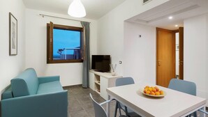 Un salon moderne comprenant un canapé, une table à manger avec des chaises, un téléviseur et une fenêtre donnant sur un beau paysage.