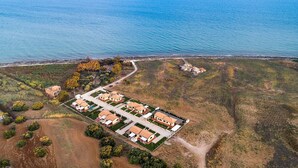 Vue aérienne d’une zone résidentielle côtière, avec des maisons, une route et une plage.
