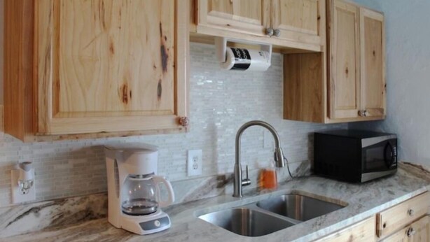 A kitchen with wooden cabinets, a coffee maker, a sink, and a microwave.