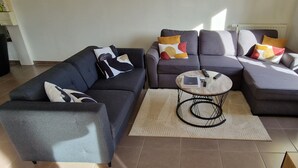 A modern living room with a sectional sofa, a coffee table, and a view of the outdoors. - Cosy room (Prévessin-Moëns)