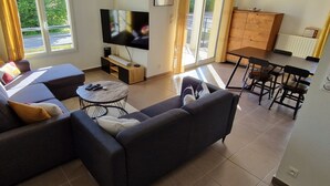 A living room with a sofa, a coffee table, a TV, and a dining area with chairs. - Cosy room (Prévessin-Moëns)