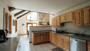 Une cuisine spacieuse avec des meubles en bois, un plan de travail en granit et un pare-feu en pierre.