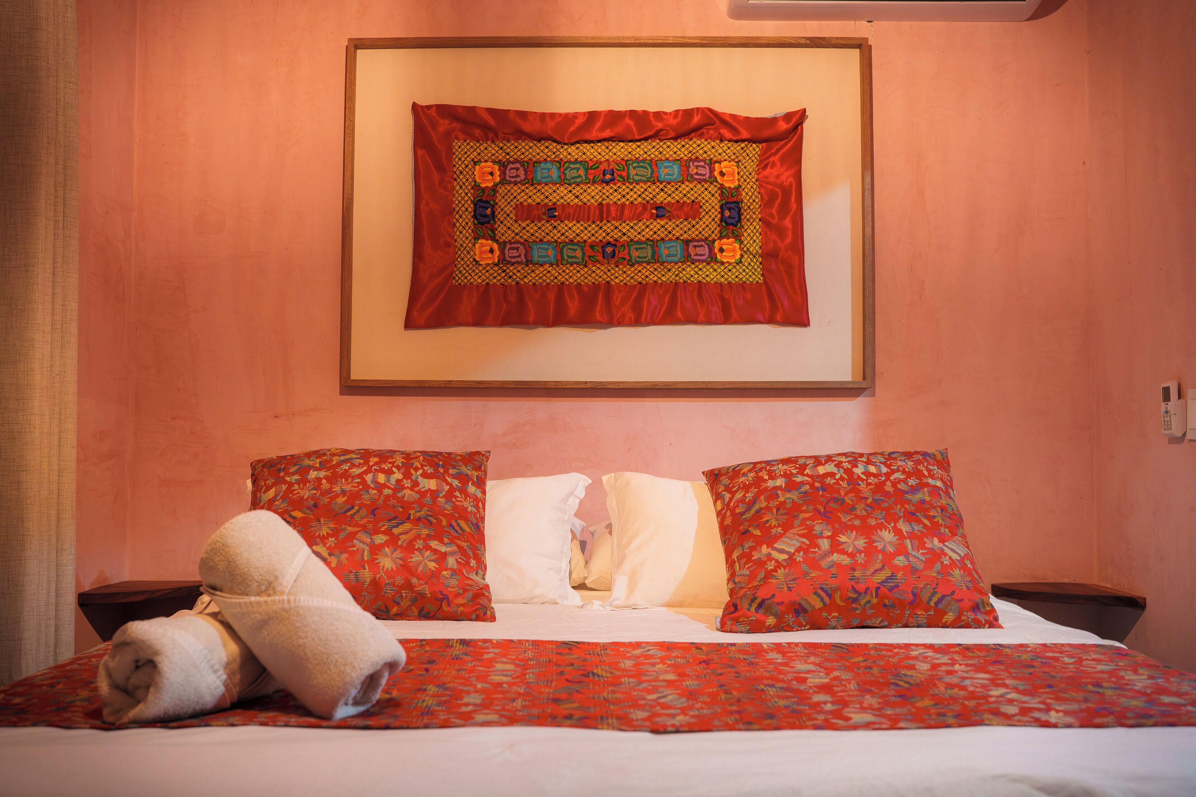 A neatly made bed with patterned pillows and a decorative wall hanging.