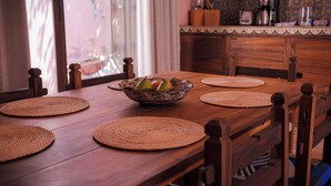 Ein Holztisch mit Obstschale, gewebten Platzsets und Stühlen.
