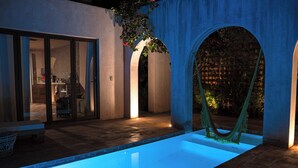 Ein Schwimmbecken mit Hängematte, einer Terrassenfläche und Blick ins Innere.