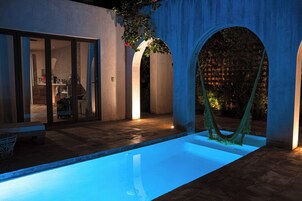 Une piscine avec un hamac, un espace patio et une vue sur l’intérieur.