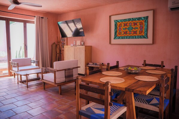 Un coin repas avec une table en bois, des chaises et un téléviseur fixé au mur.